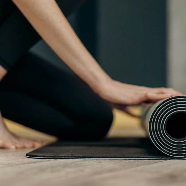 A person rolling out a yoga mat in a sunlit room.